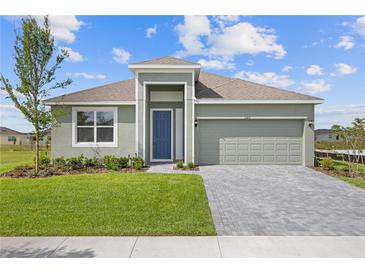 Charming single-story home featuring a manicured lawn, brick paver driveway, and a two-car garage at 1580 Gardiner St, Haines City, FL 33844
