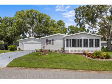 Charming home featuring a well-manicured front yard and a lovely screened-in porch for relaxing outdoors at 25333 Casa Del Lago Ln, Leesburg, FL 34748