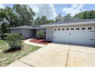 Charming single-story home with a well-maintained lawn, a two-car garage, and mature trees at 1326 Wildcat Ct, Apopka, FL 32712