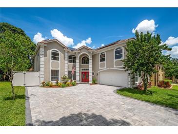 Two-story home showcasing a red front door, manicured landscaping, and a paved driveway, all under a sunny sky at 1706 Cheltenborough Dr, Orlando, FL 32835