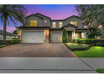 Elegant two-story home featuring a three-car garage, brick driveway and landscaped yard, perfect for curb appeal at 1938 Filly Trl, Oviedo, FL 32765