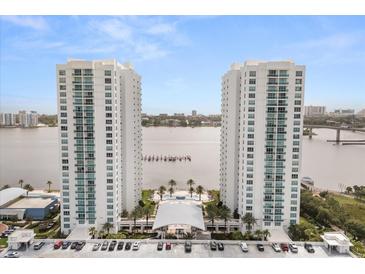 Stunning aerial view of waterfront condos with a pool and water views on a bright, sunny day at 241 Riverside Dr # 902, Holly Hill, FL 32117