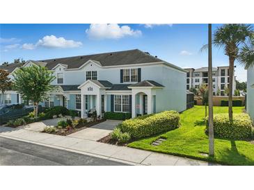 Light blue two-story townhome with a well-manicured lawn and garden at 2531 Maneshaw Ln, Kissimmee, FL 34747