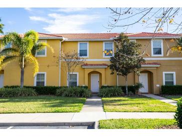 Charming townhome with vibrant yellow exterior, red tile roof, and well-manicured landscaping at 3065 Yellow Lantana Ln, Kissimmee, FL 34747