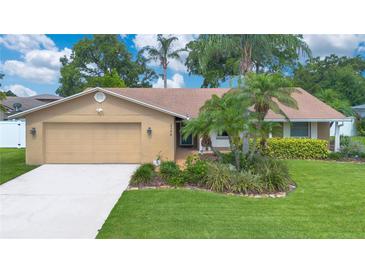 Charming single-story home featuring a two-car garage, well-manicured lawn, and lush landscaping at 4390 Carolwood St, Orlando, FL 32812