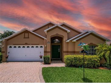 Charming single-Gathering home with a well-manicured lawn, brick driveway, and beautiful landscaping at 456 Old Bridge Cir, Davenport, FL 33897
