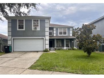 Two-story home featuring gray siding, white trim, an attached garage, and a well-maintained front yard at 512 Flower Fields Ln, Orlando, FL 32824