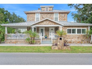 Charming two-story stone home with a metal roof, covered porch, and well-maintained landscaping at 6501 Matchett Rd, Belle Isle, FL 32809
