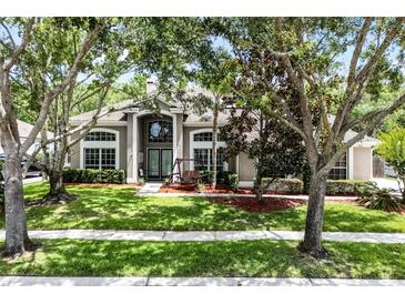 Charming home featuring a manicured lawn, mature trees, and a welcoming front entrance at 806 Spring Island Way, Orlando, FL 32828