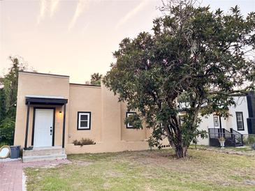 Charming beige home featuring a large tree, a white front door and black window trim at 112 Avocado Ave, Sanford, FL 32771