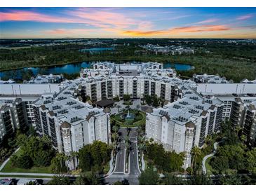 Stunning aerial view of the resort-style condo community with beautiful landscaping, lakes, and a vibrant sunset backdrop at 14501 Grove Resort Ave # 3239, Winter Garden, FL 34787