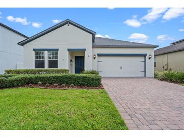 Charming single-story home with a well-manicured lawn, brick driveway, and a two-car garage at 2210 Romanum Dr, Winter Garden, FL 34787