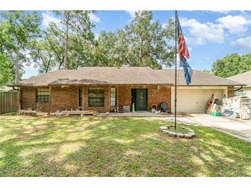 Charming single-story brick home featuring a well-maintained lawn, flag, and attached garage at 236 Longhorn Dr, Apopka, FL 32712