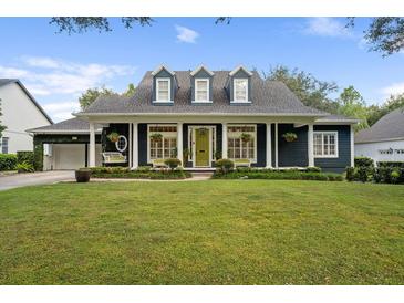 Charming two-story home featuring a lush lawn, dormer windows, and a welcoming covered front porch at 6047 Blakeford Dr, Windermere, FL 34786