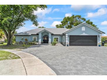 Beautiful single-story home featuring a gray brick driveway and a well-manicured lawn at 8248 Marbella View Ct, Orlando, FL 32817