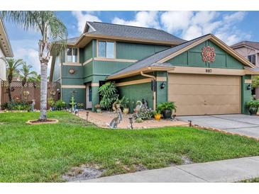 Charming two-story home with lush green lawn, palm tree and well-manicured landscaping at 887 Reedy Cv, Casselberry, FL 32707