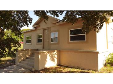 Charming single-story home featuring a classic design and neutral color scheme, shaded by mature trees at 1020 E Main St, Haines City, FL 33844