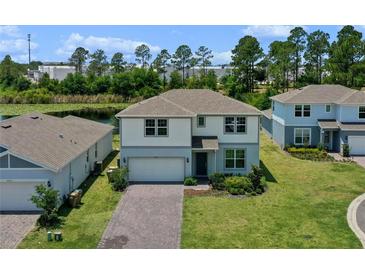 Charming two-story home featuring a brick driveway, manicured lawn, and serene water view at 17319 Million Lakes Ct, Clermont, FL 34714