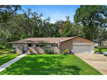 Charming single-story home featuring a brick facade, lush green lawn, and mature trees under a bright, sunny sky at 203 N Sweetwater Blvd, Longwood, FL 32779