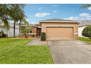 Inviting single-story home featuring a two-car garage and well-manicured front lawn with mature palm trees at 2628 Balforn Tower Way, Winter Garden, FL 34787