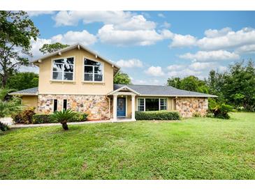 Charming two-story home with stone accents, beautiful landscaping, and a well-maintained lawn at 3102 Cecelia Dr, Apopka, FL 32703