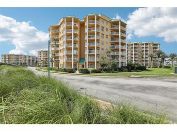 Beautiful yellow condominium building featuring multiple balconies with manicured landscaping and blue skies at 4650 Links Village Dr # B103, Ponce Inlet, FL 32127