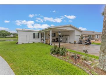 Charming home featuring a covered carport, lush lawn and garden with a tranquil pond view in the background at 5305 Ingleside, Leesburg, FL 34748