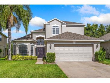 Charming two-story home with lush green lawn, landscaped garden, and attached two-car garage at 9966 Hidden Dunes Ln, Orlando, FL 32832