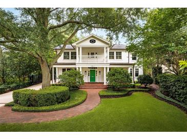 Charming two-story home with a welcoming front porch, manicured landscaping, and a vibrant green front door at 1011 Lake Davis Dr, Orlando, FL 32806