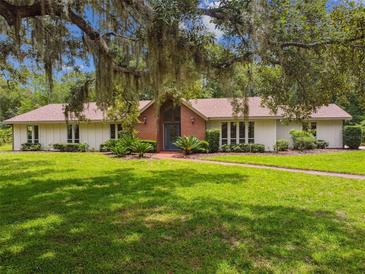 Charming single-story home boasts a lush front yard, mature trees, and a brick facade entry at 207 S Sweetwater Blvd, Longwood, FL 32779