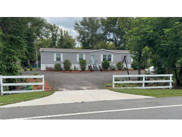 Charming single-story home with gray siding, a graveled yard, and a white picket fence at 31701 State Road 44 Sr-44, Eustis, FL 32736