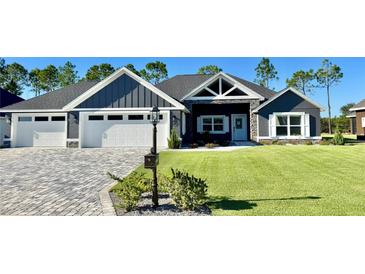 Beautiful home featuring a well-manicured lawn, attractive landscaping, and a three-car garage at 6449 Sw 180Th Cir, Dunnellon, FL 34432