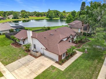 A beautiful aerial view of a single-Gathering home, a private lake, and a well-manicured landscape at 700 Wyckliffe Pl, Winter Springs, FL 32708