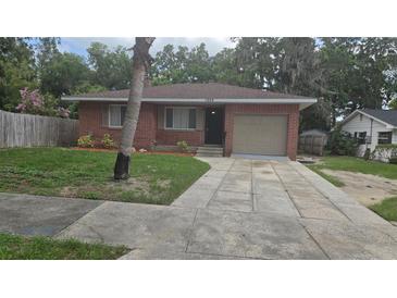 Charming brick home featuring an attached garage and a well-kept front yard with mature landscaping at 1205 Deleon Ave, Leesburg, FL 34748