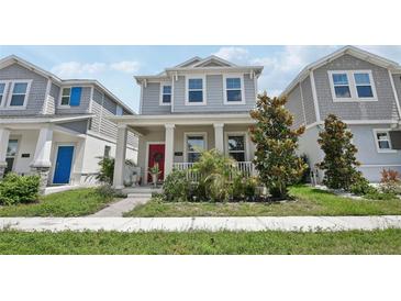 Charming two-story home with a welcoming front porch, beautiful landscaping, and a vibrant red front door at 2345 Volunteer Ave, Kissimmee, FL 34744