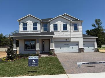 Two-story home boasts a three-car garage, gray accents, and a welcoming front porch at 441 Lady Palm St, Apopka, FL 32703