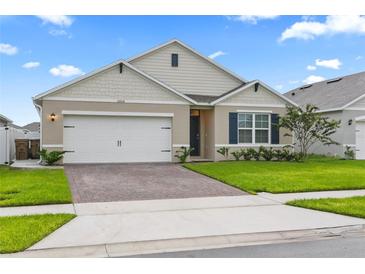 Charming single-story home featuring a well-manicured lawn, brick driveway, and an attached two-car garage at 5808 Arboretum St, St Cloud, FL 34771