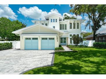 Stunning two-story home with a well-manicured lawn, blue garage doors, and elegant architectural details at 1820 Glencoe Rd, Winter Park, FL 32789
