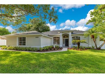 Charming single story home featuring a well-manicured lawn, garden beds, and a walkway to the front door at 2024 Flaming Arrow Ct, Fern Park, FL 32730