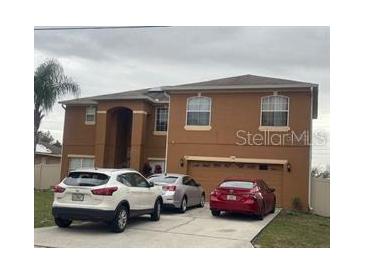 Two-story tan home with an attached two-car garage and driveway parking at 547 Big Sioux Ct, Kissimmee, FL 34759