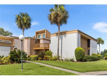 Condo exterior with manicured landscaping and palm trees against a blue sky at 1051 S Highland St # 7D, Mount Dora, FL 32757