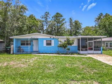 Charming single-story home with a blue exterior, screened in porch, and well-maintained lawn at 2728 Hertha Ave, Orlando, FL 32826