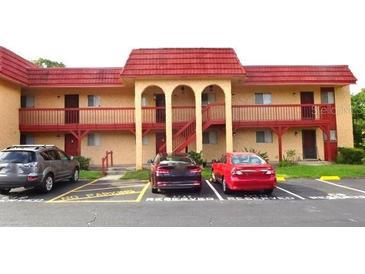 Apartment building featuring a red roof, balcony, and reserved parking spaces in the front at 2864 N Powers Drive # 156, Orlando, FL 32818