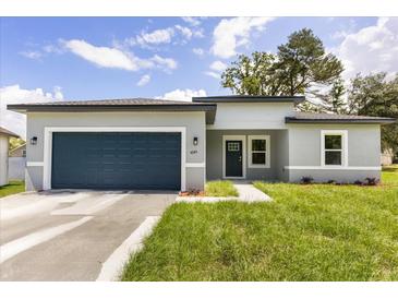 Charming single-story home with a blue garage door, well-kept lawn, and a modern gray exterior at 4345 Sw 143Rd Lane Rd, Ocala, FL 34473