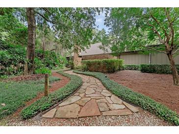 Inviting stone pathway leading to the home, framed by lush greenery and mature trees at 4702 Shorecrest Dr, Orlando, FL 32817