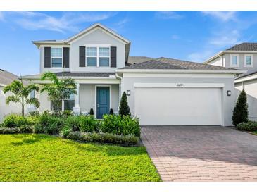 Charming two-story home featuring lush landscaping, brick driveway and two car garage at 609 Big Pine Ave, Minneola, FL 34715
