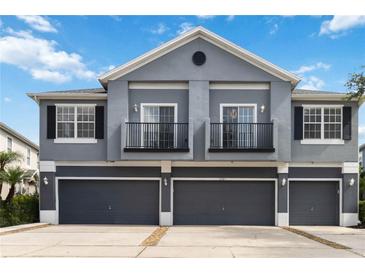 Stylish townhome featuring a gray exterior, multiple garage doors, and quaint second-story balconies at 6484 S Goldenrod Rd # 41A, Orlando, FL 32822