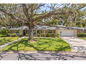 Charming single story home featuring a lush front yard with a well manicured lawn, mature tree, and inviting covered porch at 708 Valencia Ct, Winter Garden, FL 34787