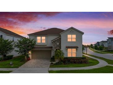 Charming two-story home featuring stone accents, a paved driveway, and lush landscaping at dusk at 8951 Hilton Ridge Ave, Kissimmee, FL 34747