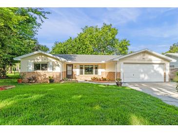 Charming single-story home featuring a well-manicured lawn, brick accents, and an attached garage at 241 Brittany Ave, Port Orange, FL 32127